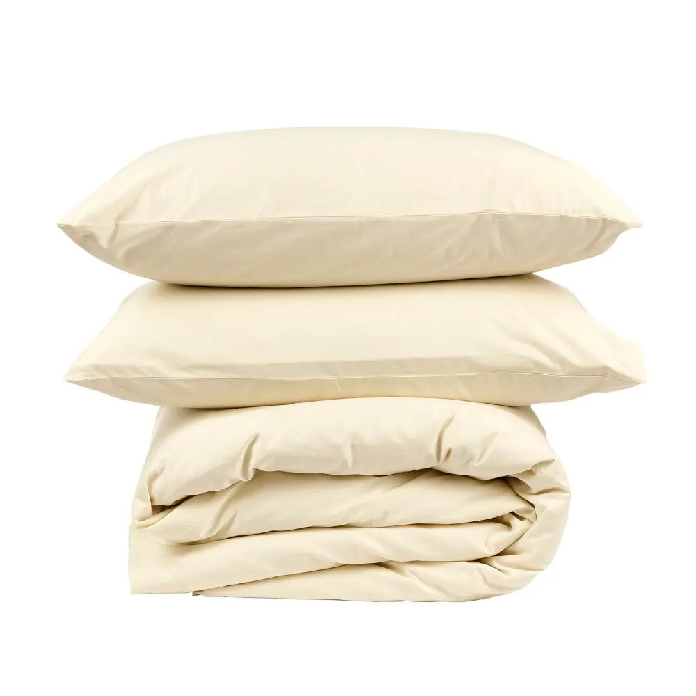 A duvet encased in a cream coloured hotel quality duvet cover with two pillows encased in Hotel Pure Luxury cream coloured pillowcases on top of it.