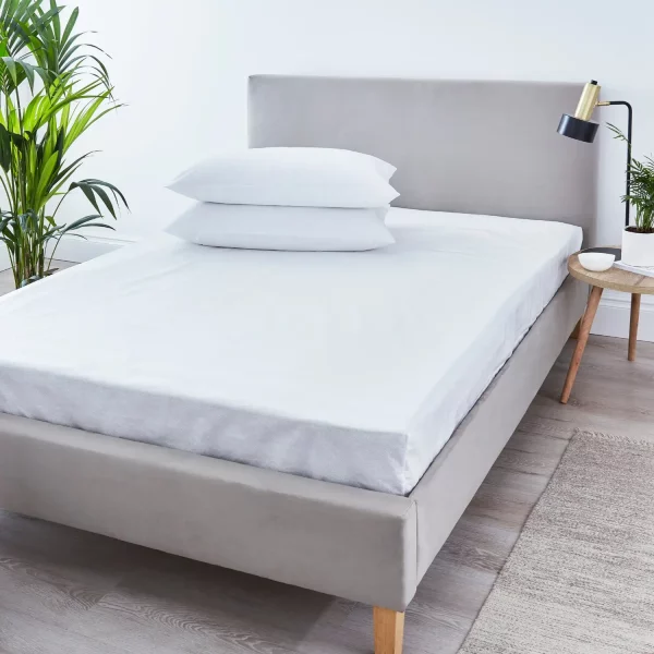 A fully enclosed anti-allergy mattress protector from the Martex range on a bed with two pillows on it.