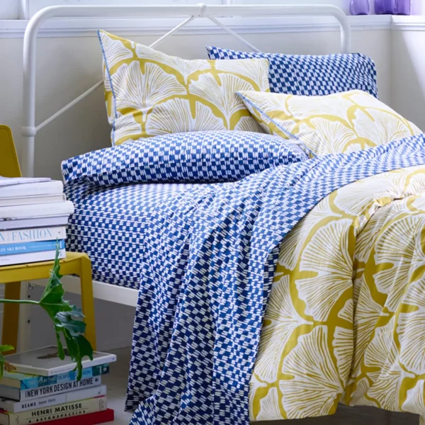 A golden mustard feather palm patterned duvet cover and pillowcase. Also pictures is a painted blue check fitted sheet, which is available separately.