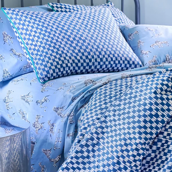 A painted blue check duvet cover set with painted blue pillowcases. Also visible is a Zebras in Love fitted sheet, available separately.