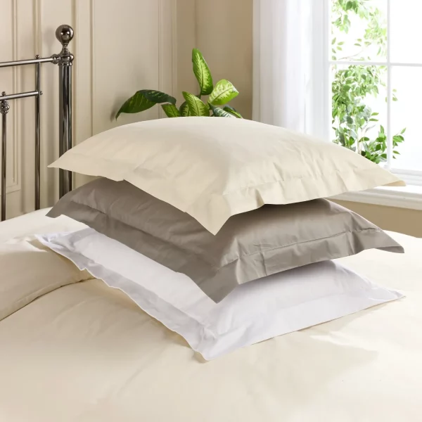 Three Hotel Pure Luxury 480 thread count Oxford pillowcases encasing pillows stacked on top of each other. In crea, grey and white.