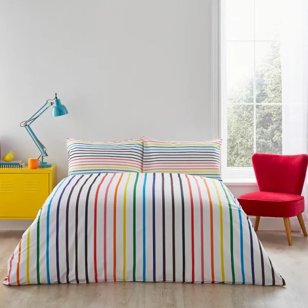 A multi-coloured rainbow striped Pride themed duvet cover and pillowcase set from Martex Pride covering a bed in a modern bedroom.