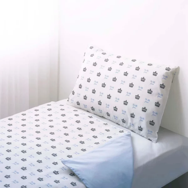 A white duvet cover and pillowcase. It features a print of small crowns all across it with blue writing that says 'My Little Prince'.