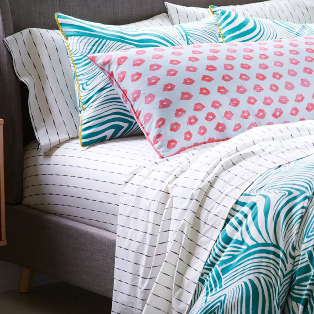 A green zebra marble patterned duvet cover and pillowcase set. There is also a vintage stripe fitted sheet and a body pillow with red lips visible.