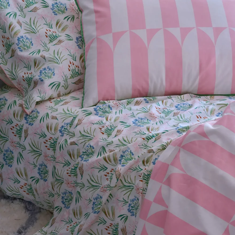 A close up of a waverly tile pink duvet cover and pillowcases. Also pictured is a green floral fitted sheet.