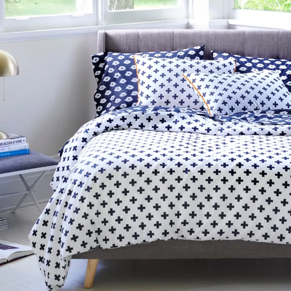 A white duvet cover and pillowcases printed with black crosses.