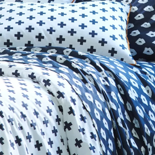 A close up of a white duvet cover and pillowcases printed with black crosses.