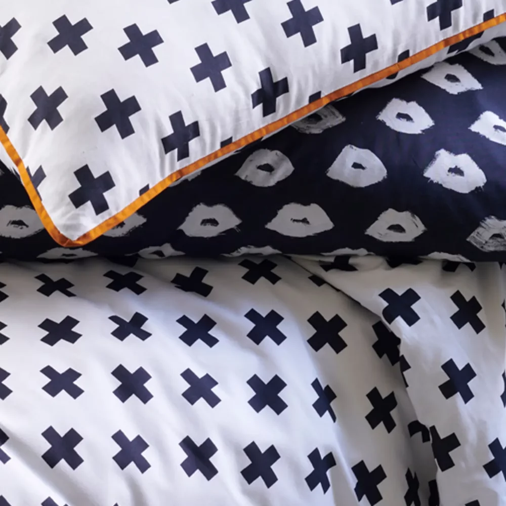 A close up of a white duvet cover and pillowcases printed with black crosses.