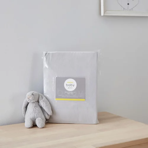 A grey moses basket fitted sheet from Martex Baby in its packaging. There is a grey toy bunny next to it.