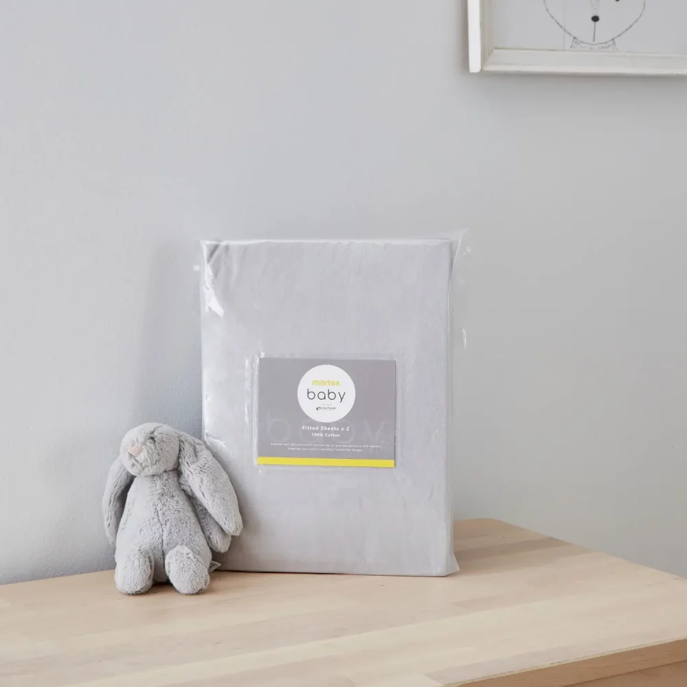 A grey pram fitted sheet from Martex Baby in its packaging. There is a grey toy bunny next to it.