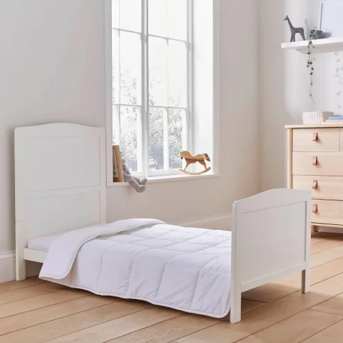 A Martex Baby anti-allergy 4 tog cot duvet sitting on a bed in a child's bedroom. There is also a pillow sitting against the headboard.