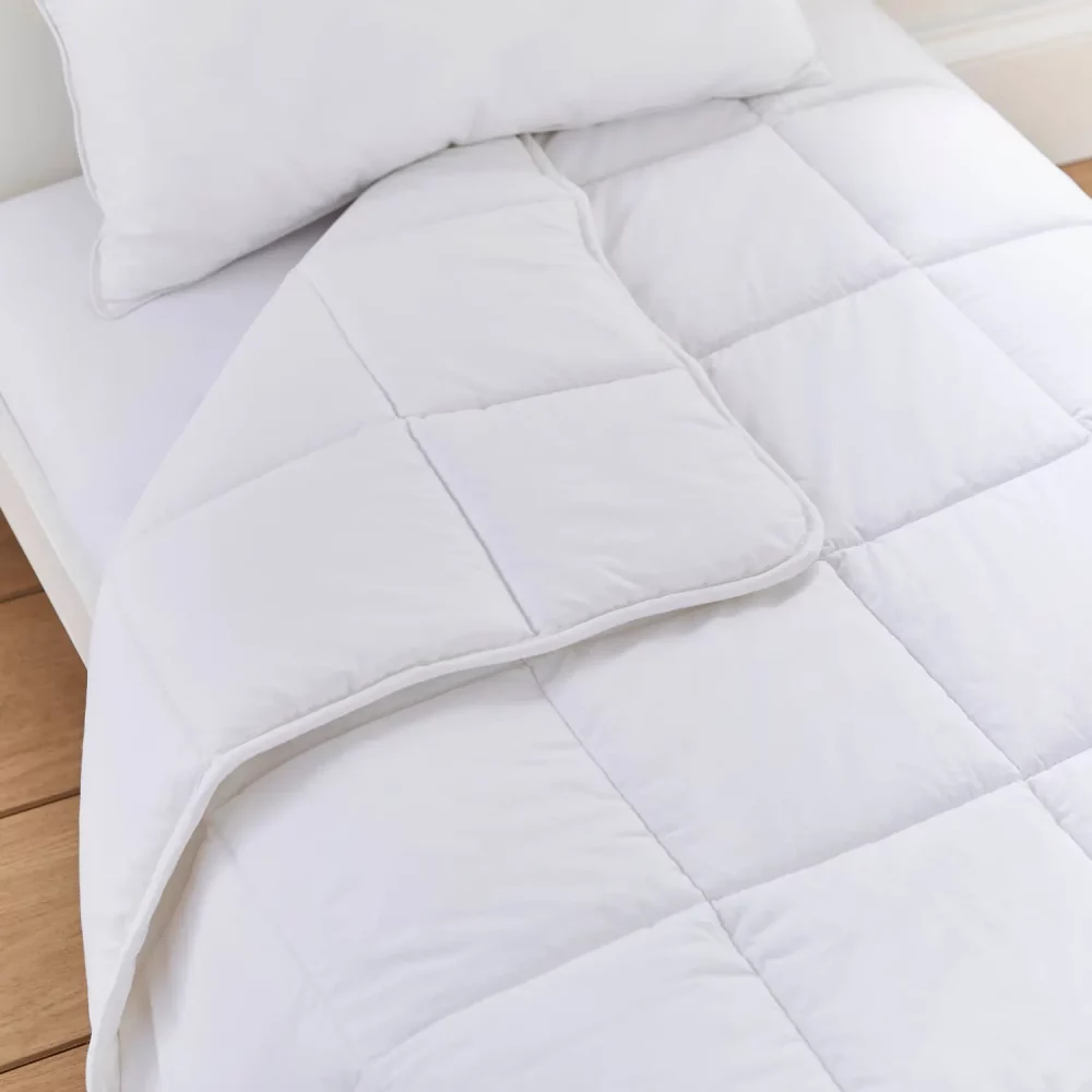 A close up look at a white anti-allergy 4 tog cot duvet from Martex Baby. The duvet has a square grid design. The duvet is slightly folded back.