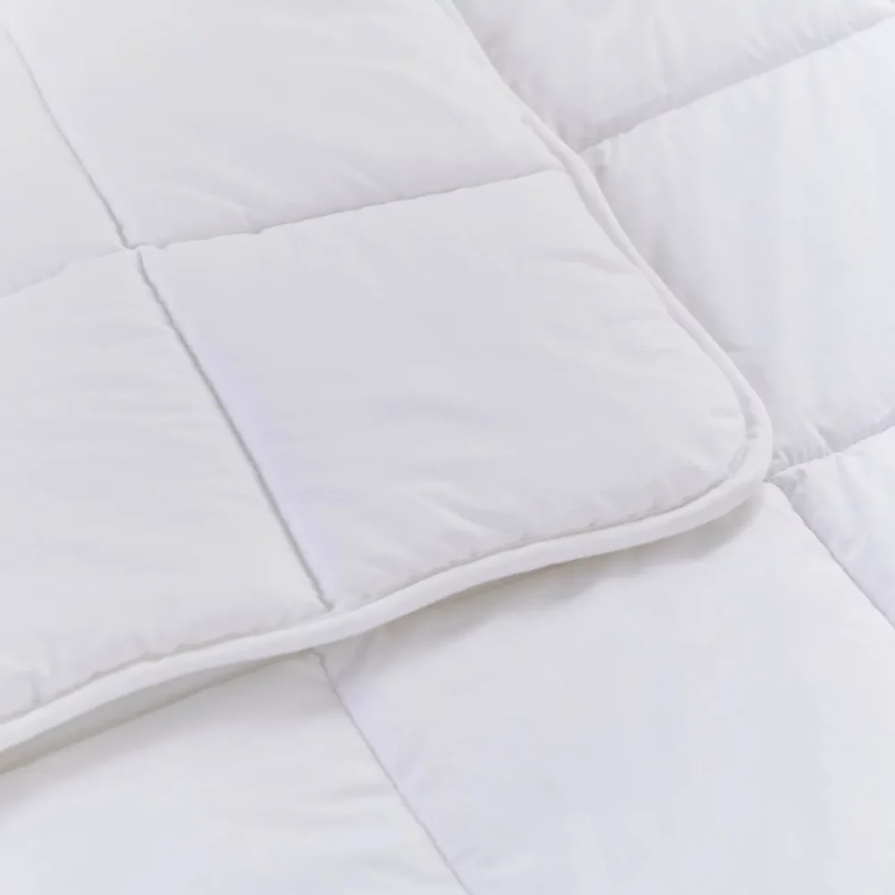 A close up look at a white anti-allergy 4 tog cot duvet from Martex Baby. The duvet has a square grid design.