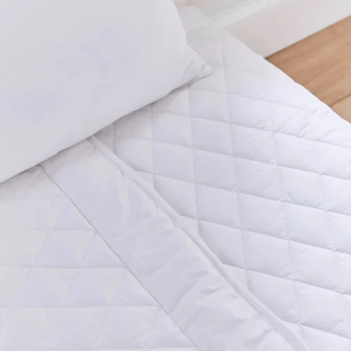 A close up look at a white 4 tog cot bed wool duvet from Martex Baby. The duvet has a diamond grid design.