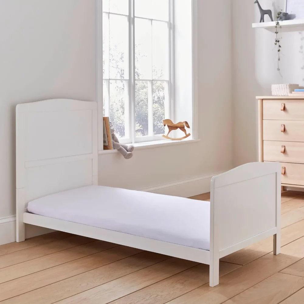 A white fitted sheet covering the mattress on a bed in a child's bedroom.