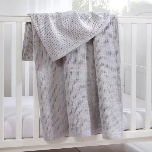 A grey Clair De Lune cotton cellular blanket hanging from a cot