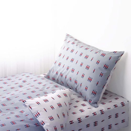 A white duvet cover and pillowcase set from Rachel Riley. It features a print of small toy beefeater soldiers in red and blue.