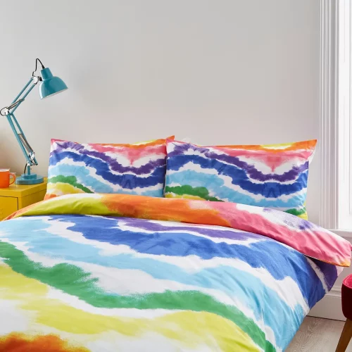 A multi-coloured rainbow Pride themed duvet cover and pillowcase set from Martex Pride covering a bed in a modern bedroom.