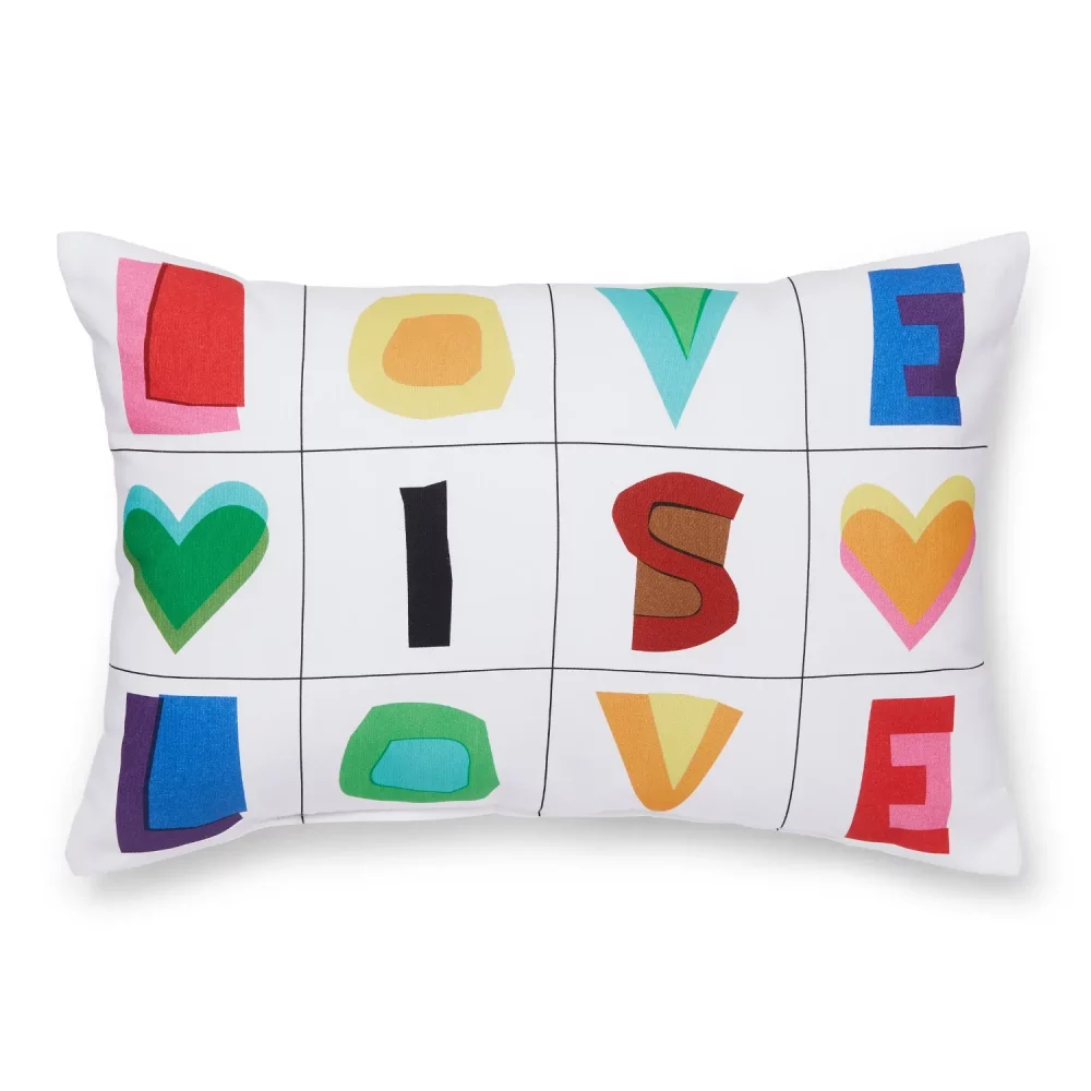 A white cushion from Martex Pride. It features a series of squares with multi-coloured letters and love hearts in them, spelling out the slogan 'Love is Love'. Features a white background.